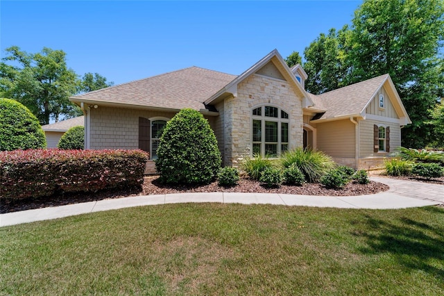 view of front of home with stone siding, a front yard, and a shingled roof