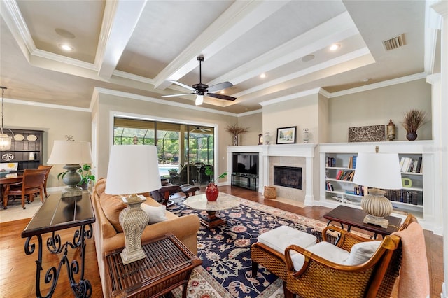 living room with wood finished floors, ceiling fan, crown molding, a fireplace, and beam ceiling
