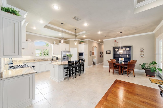 kitchen with appliances with stainless steel finishes, a kitchen breakfast bar, a sink, a center island, and white cabinets