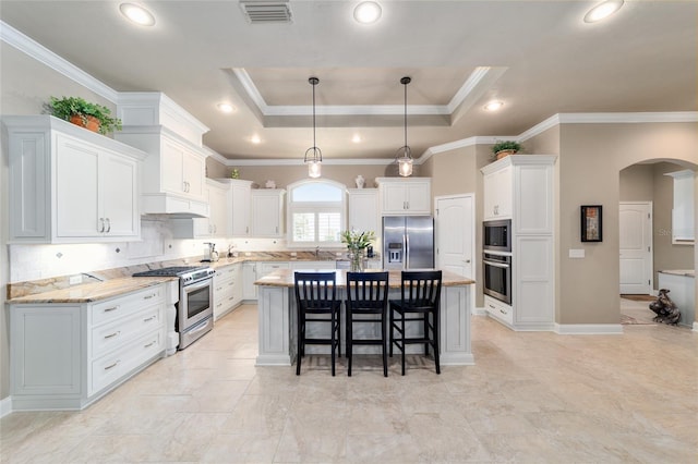 kitchen featuring stainless steel appliances, arched walkways, a center island, white cabinetry, and ornamental molding