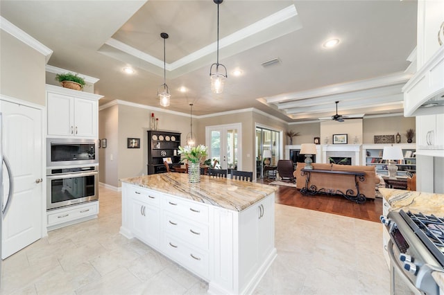 kitchen with stainless steel appliances, a raised ceiling, french doors, a ceiling fan, and crown molding