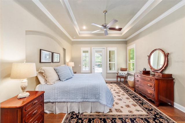 bedroom featuring wood finished floors, a raised ceiling, access to exterior, baseboards, and ornamental molding