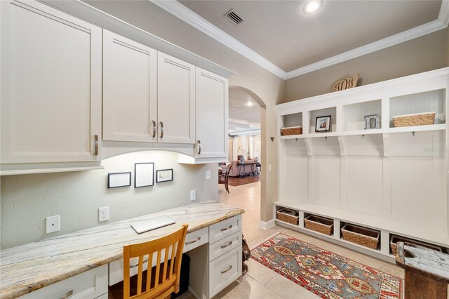 office featuring arched walkways, built in desk, crown molding, light tile patterned flooring, and recessed lighting