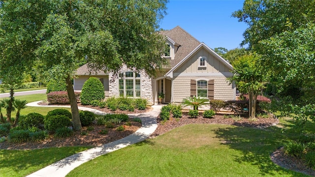 view of front of home with a front yard, stone siding, and board and batten siding
