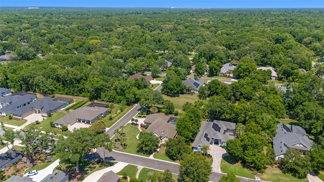 aerial view of property and surrounding area featuring a heavily wooded area and nearby suburban area