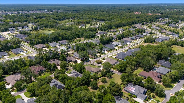 aerial view of property and surrounding area with nearby suburban area and a heavily wooded area