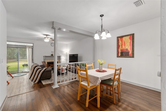 938 NW 42nd Ter, Gainesville, FL 32605 - dining space featuring dark wood finished floors, ceiling fan, a tile fireplace, and decorative columns
