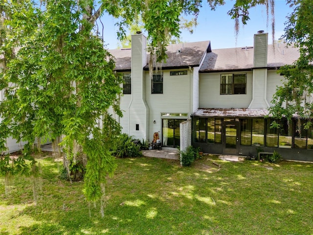938 NW 42nd Ter, Gainesville, FL 32605 - back of property with a sunroom, a chimney, and a lawn