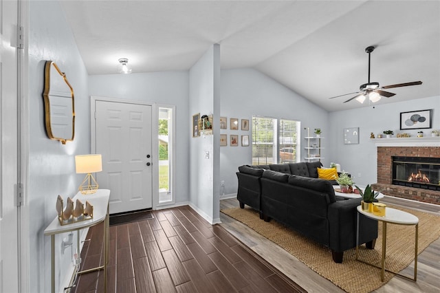 entrance foyer with a brick fireplace, dark wood-type flooring, baseboards, ceiling fan, and vaulted ceiling
