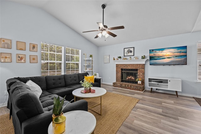 living area with a fireplace, lofted ceiling, a ceiling fan, and wood finished floors