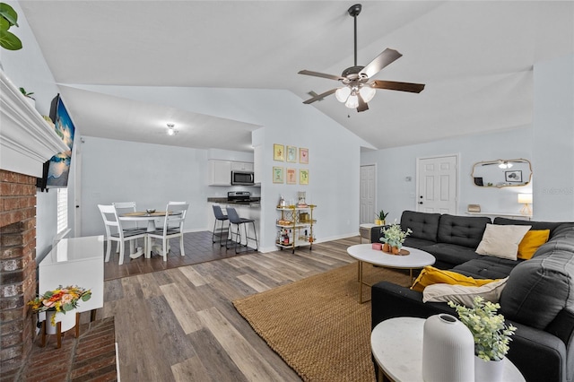 living area featuring lofted ceiling, baseboards, a ceiling fan, and wood finished floors