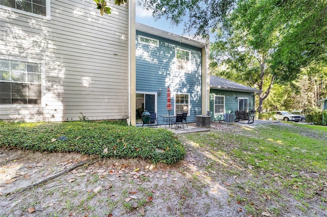 back of property with central AC unit and a patio