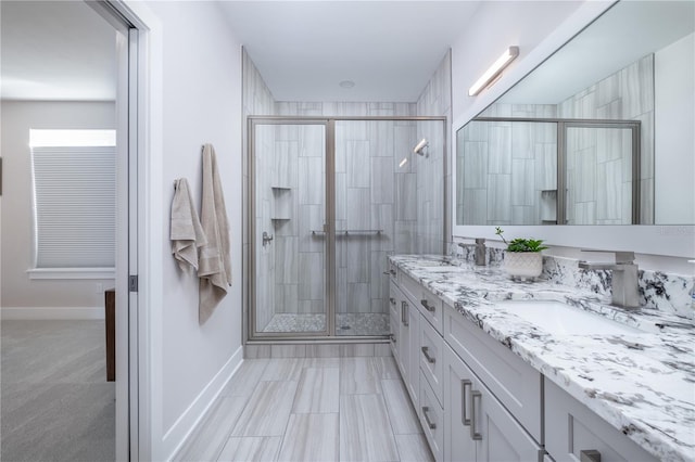 full bath featuring a sink, double vanity, baseboards, and a shower stall