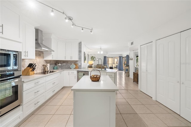205 Pacifica Vista Way Unit 205, Saint Augustine, FL 32080 - kitchen with a peninsula, light countertops, wall chimney range hood, appliances with stainless steel finishes, and tasteful backsplash