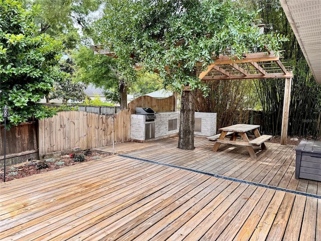 wooden deck featuring exterior kitchen, a fenced backyard, and a grill