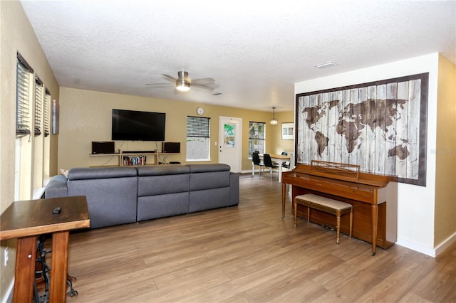 living room featuring a ceiling fan, wood finished floors, a textured ceiling, and baseboards