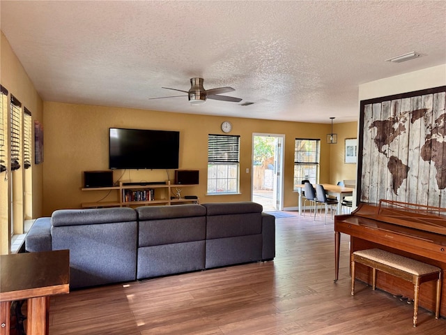 living room featuring ceiling fan, wood finished floors, and a textured ceiling