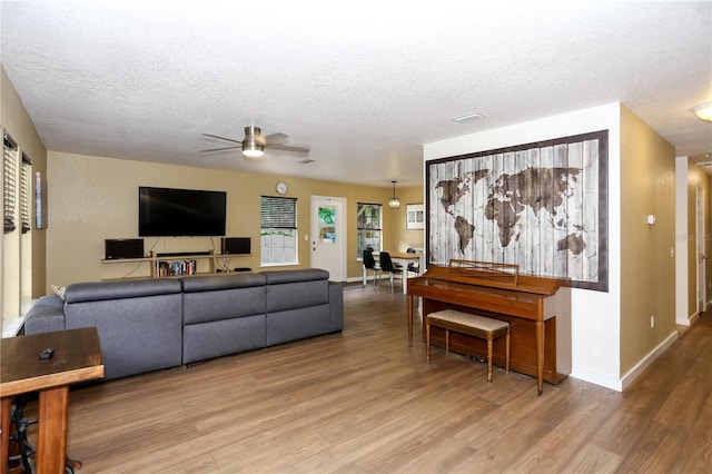 living area featuring wood finished floors, ceiling fan, a textured ceiling, and baseboards