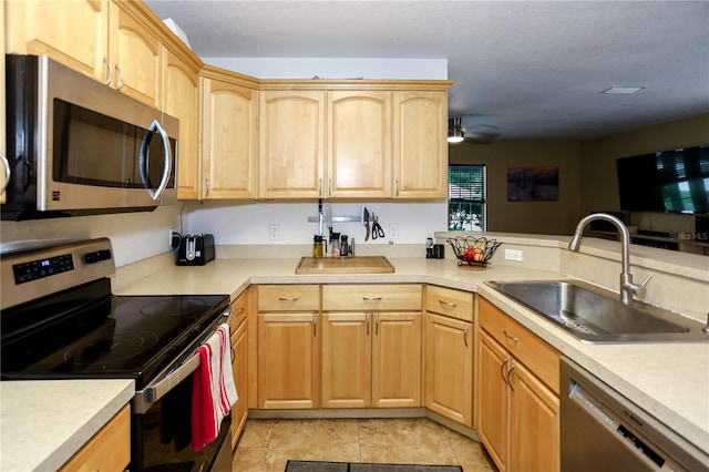 kitchen with stainless steel appliances, light brown cabinetry, a sink, and light countertops