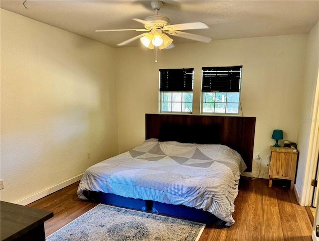 bedroom featuring wood finished floors, baseboards, and a ceiling fan