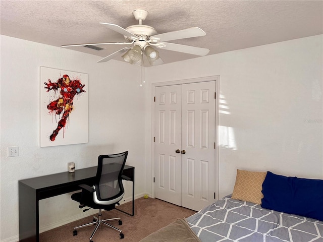 bedroom featuring carpet flooring, a textured ceiling, a closet, an office area, and a ceiling fan