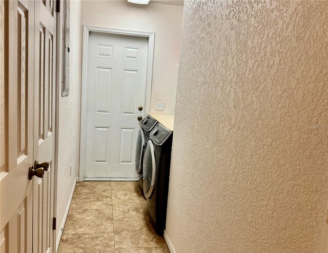 laundry room featuring separate washer and dryer, a textured wall, and baseboards