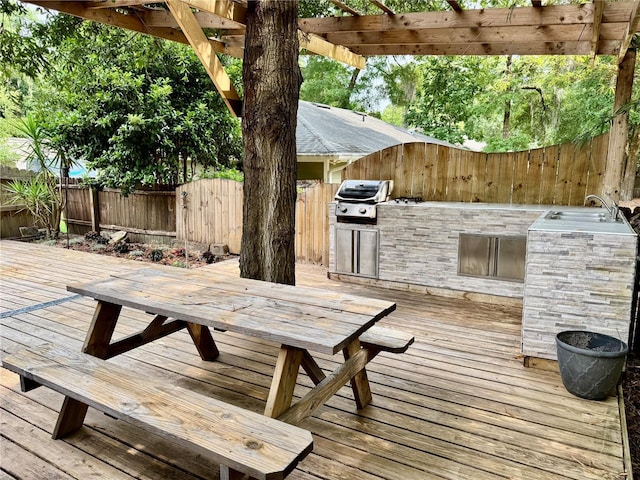 wooden deck featuring an outdoor kitchen, grilling area, a fenced backyard, outdoor dining area, and a pergola