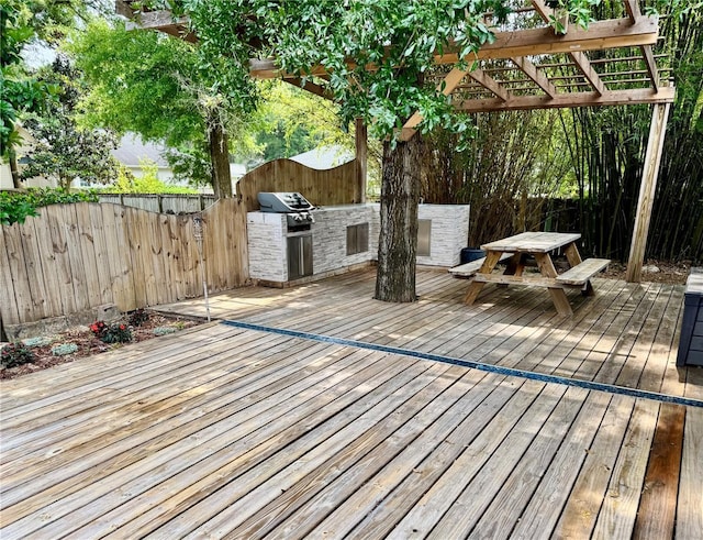 wooden terrace with an outdoor kitchen, a fenced backyard, grilling area, and outdoor dining area