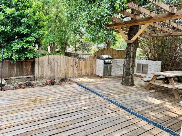 deck featuring a fenced backyard, an outdoor kitchen, a pergola, and grilling area