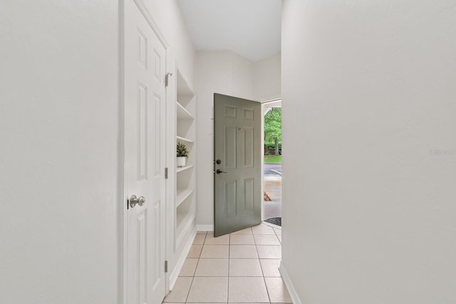doorway with light tile patterned floors and baseboards