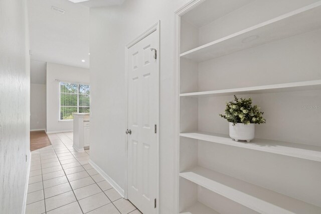 corridor with light tile patterned floors and baseboards