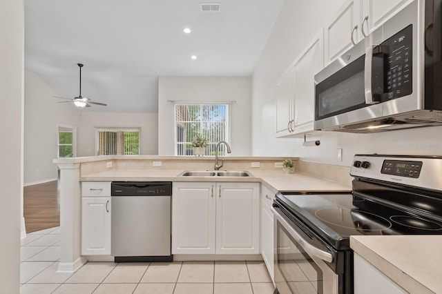 kitchen featuring appliances with stainless steel finishes, a sink, a peninsula, white cabinets, and recessed lighting
