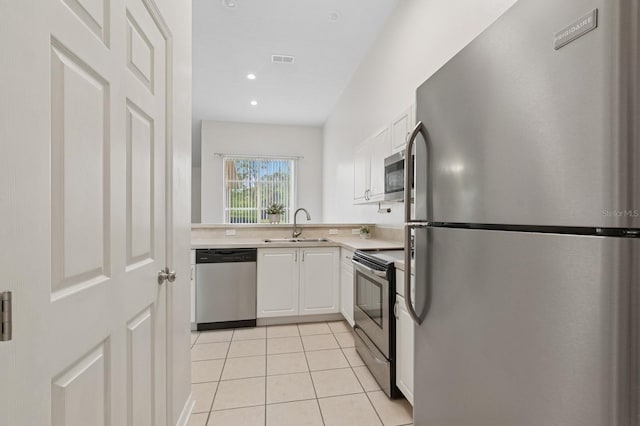 kitchen with appliances with stainless steel finishes, a sink, light countertops, white cabinetry, and light tile patterned floors