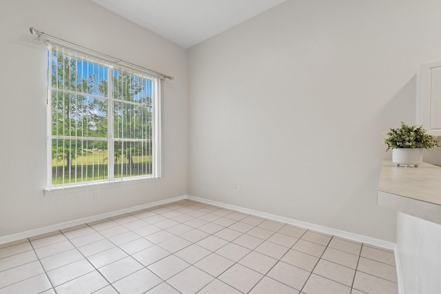 empty room featuring baseboards and light tile patterned floors