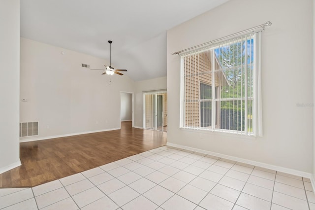 spare room featuring light wood-style flooring, a ceiling fan, vaulted ceiling, and baseboards
