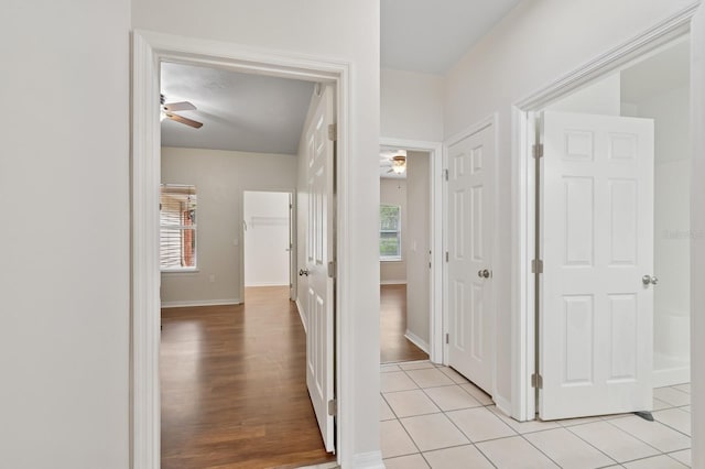 corridor with baseboards and light tile patterned floors