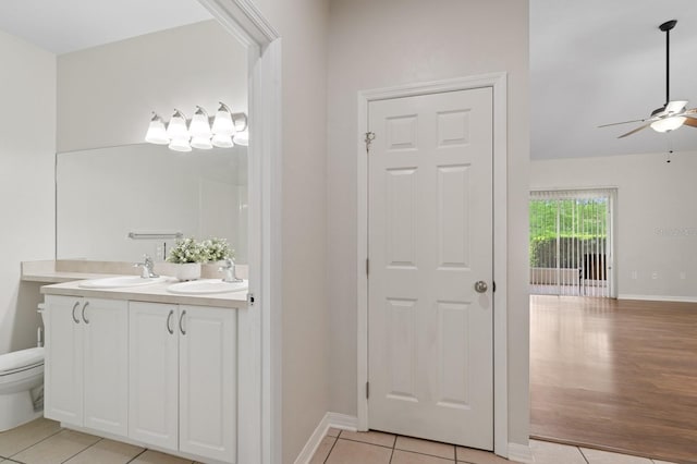 bathroom with ceiling fan, double vanity, tile patterned flooring, and baseboards