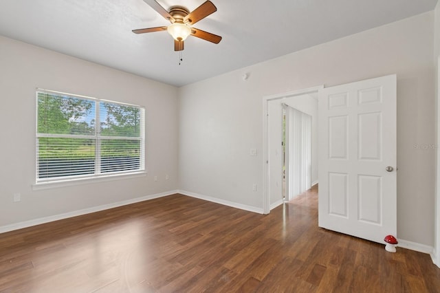 spare room with ceiling fan, dark wood-style floors, and baseboards