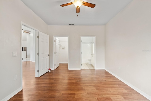 unfurnished bedroom featuring light wood-style floors, baseboards, and a walk in closet