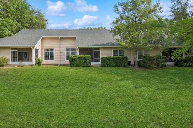 back of house with a sunroom, a lawn, and a shingled roof