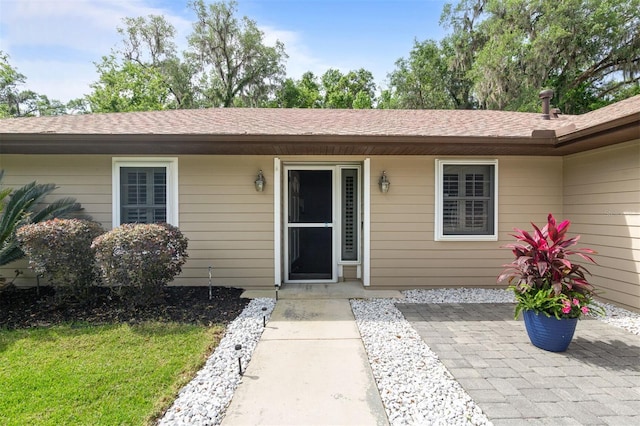 9505 NW 4th Pl, Gainesville, FL 32607 - view of exterior entry featuring a shingled roof and a patio