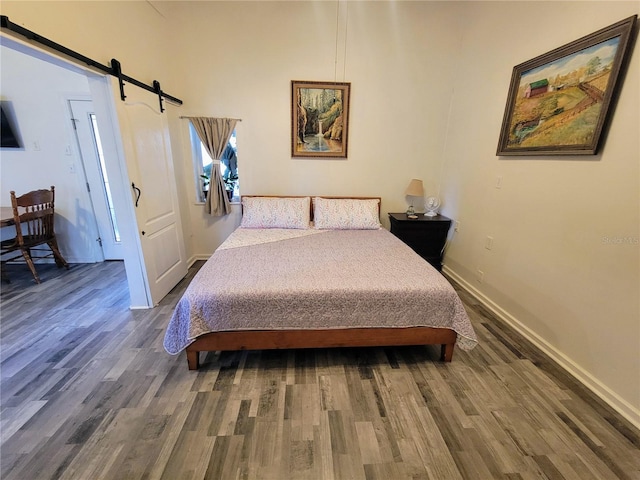 9150 SW 151st Ln, Archer, FL 32618 - bedroom featuring a barn door, wood finished floors, and baseboards