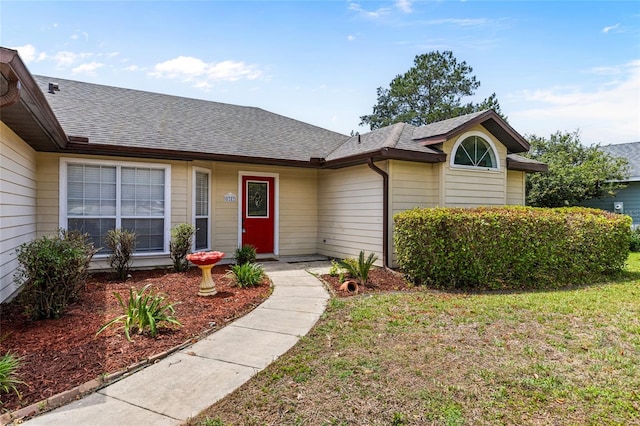 ranch-style home featuring a shingled roof and a front lawn