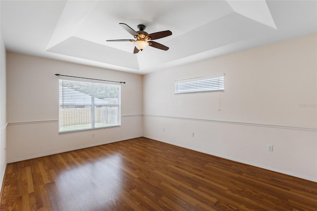 unfurnished room with a ceiling fan, baseboards, wood finished floors, and a raised ceiling