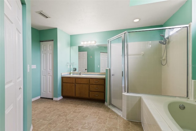 bathroom with baseboards, visible vents, a shower stall, a garden tub, and vanity