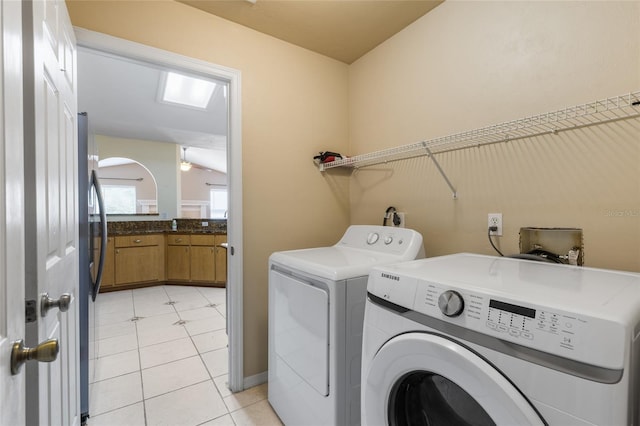 washroom featuring laundry area, washer and dryer, light tile patterned flooring, and a skylight