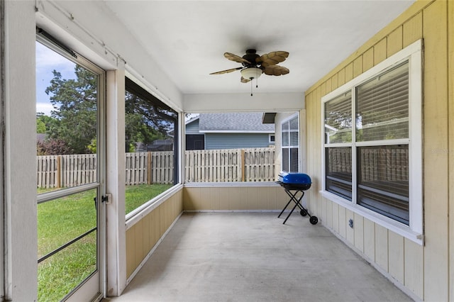 unfurnished sunroom featuring a ceiling fan and plenty of natural light