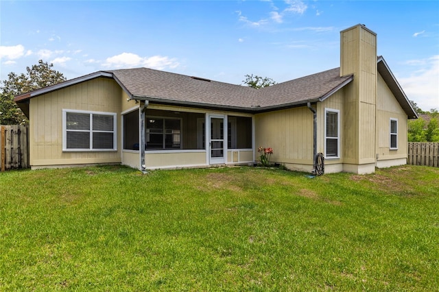 back of property with a sunroom, a chimney, fence, and a lawn