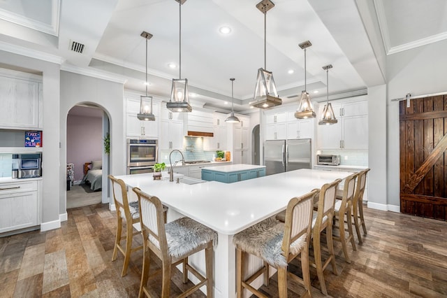 2734 SW 105th St, Gainesville, FL 32608 - kitchen featuring appliances with stainless steel finishes, a large island with sink, arched walkways, a sink, and recessed lighting