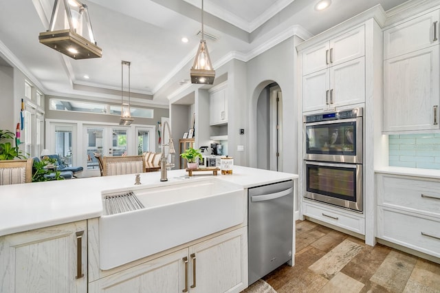2734 SW 105th St, Gainesville, FL 32608 - kitchen with stainless steel appliances, a sink, a raised ceiling, ornamental molding, and light countertops